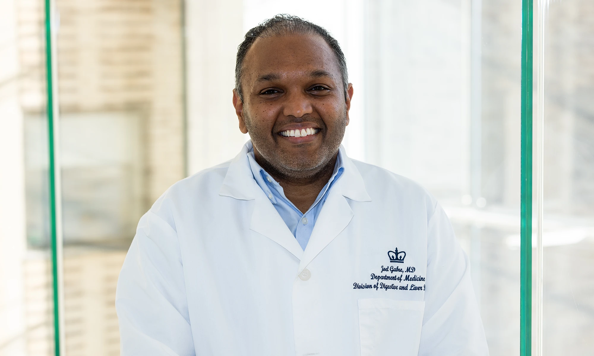 A headshot of Joel Gabre, MD, smiling at the camera in his white coat.