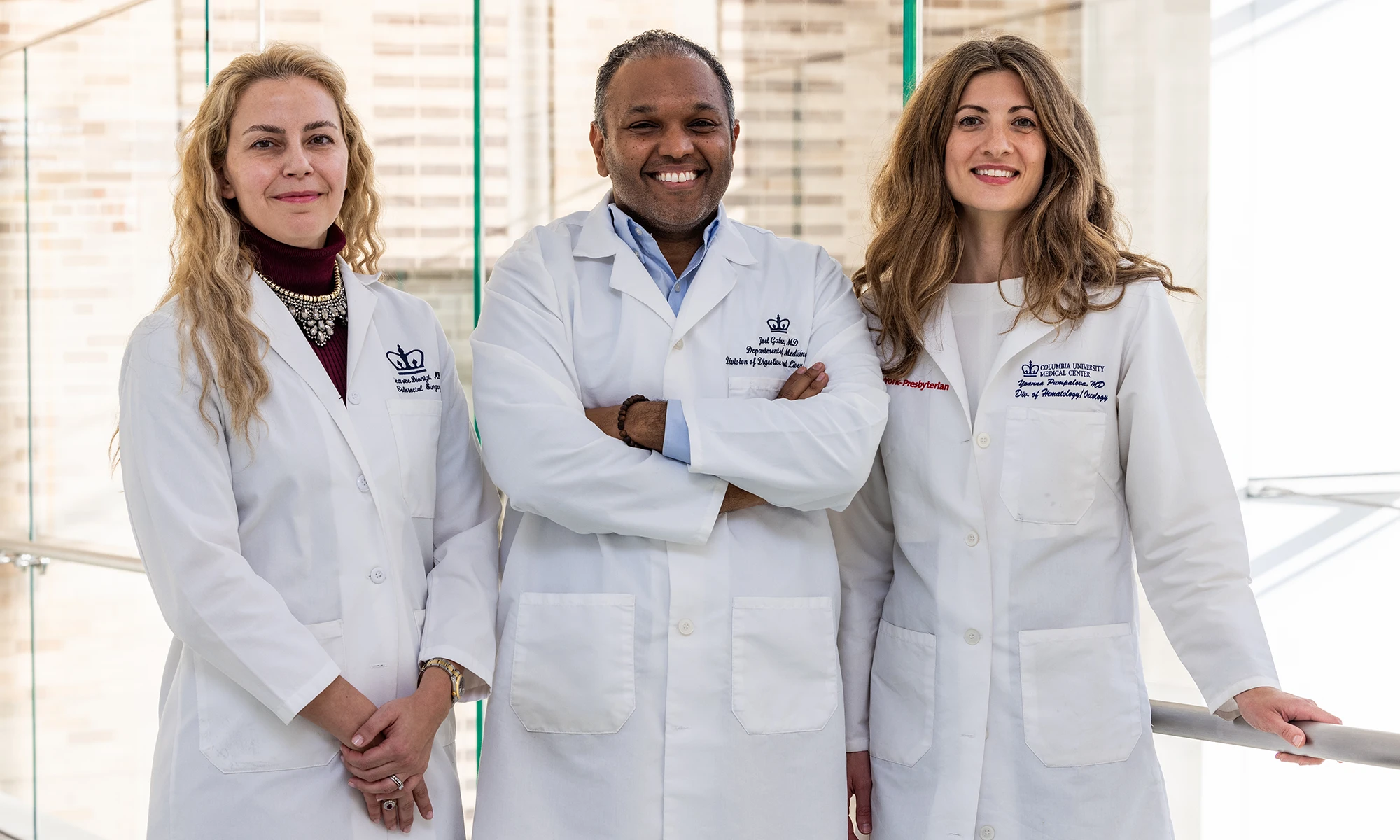 Three Columbia physicians stand side by side, smiling at the camera in their white coats. From left to right: Beatrice Dionigi, MD, FACS, FASCRC, Joel Gabre, MD, and Yoanna Pumpalova, MD.