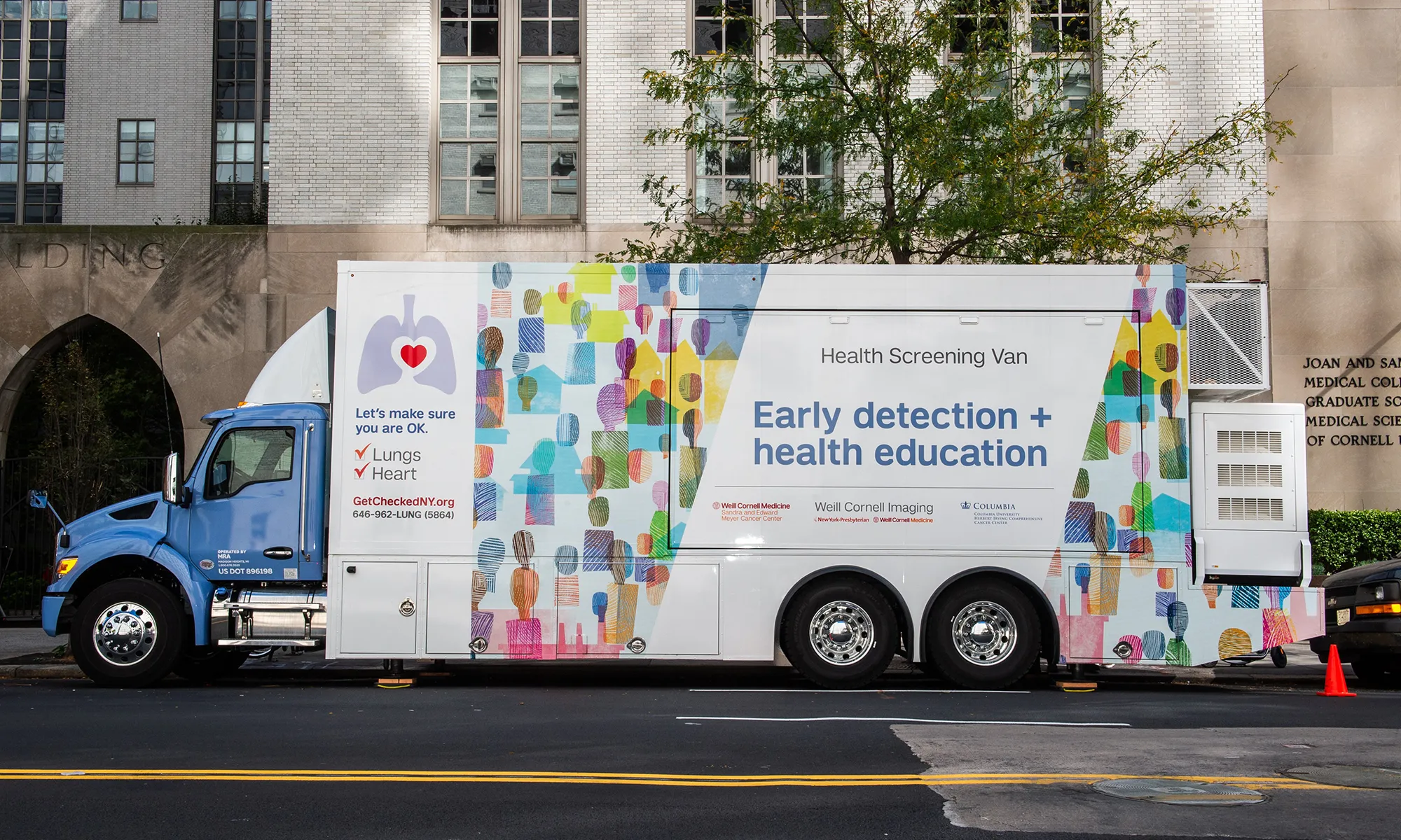 A white mobile health screening van parked on a New York City street, featuring colorful artwork and text that reads “Early detection + health education.” The van displays logos for Weill Cornell Medicine, NewYork-Presbyterian, and Columbia University Herbert Irving Comprehensive Cancer Center.