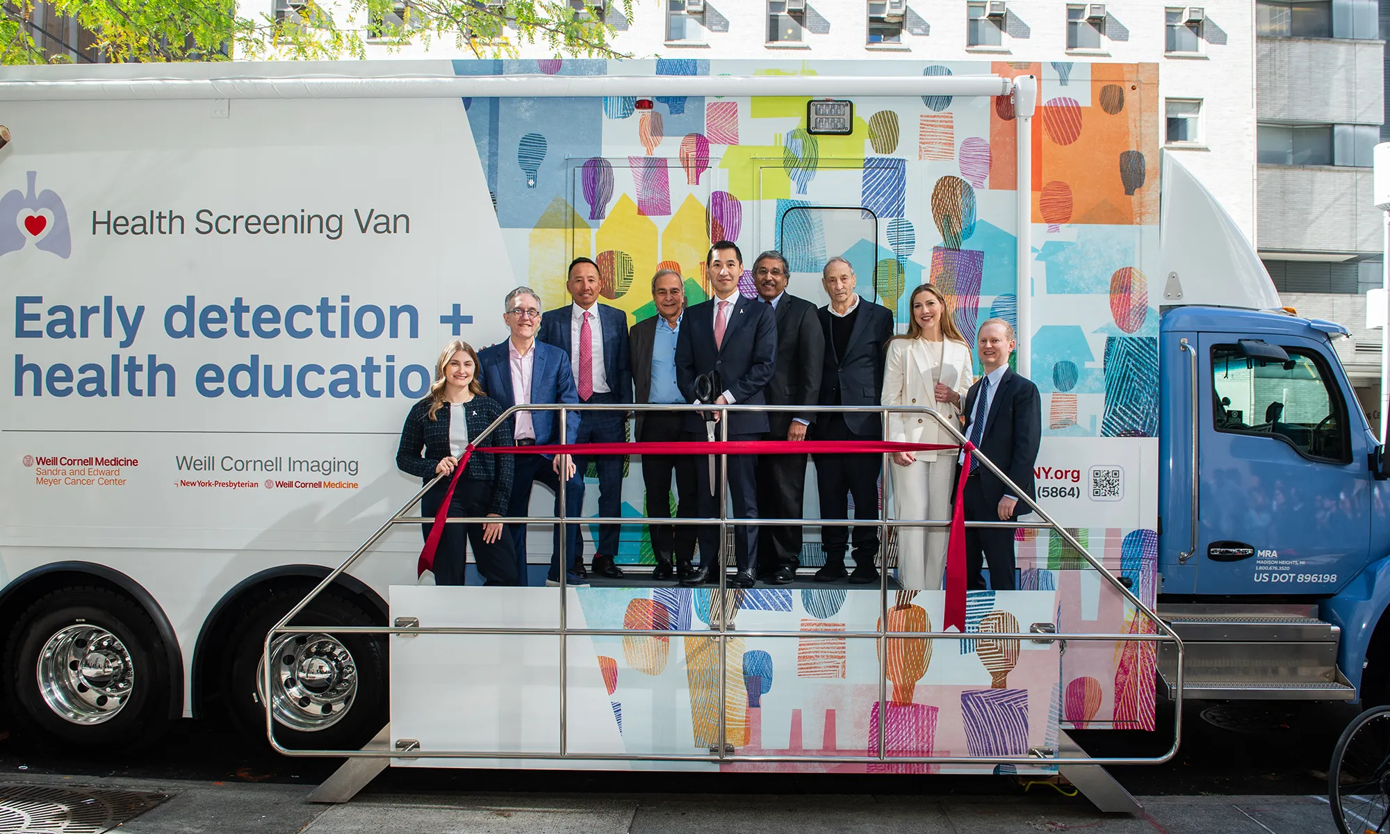 A group of institutional leaders and partners stand in front of the mobile lung screening van during the ribbon-cutting ceremony.