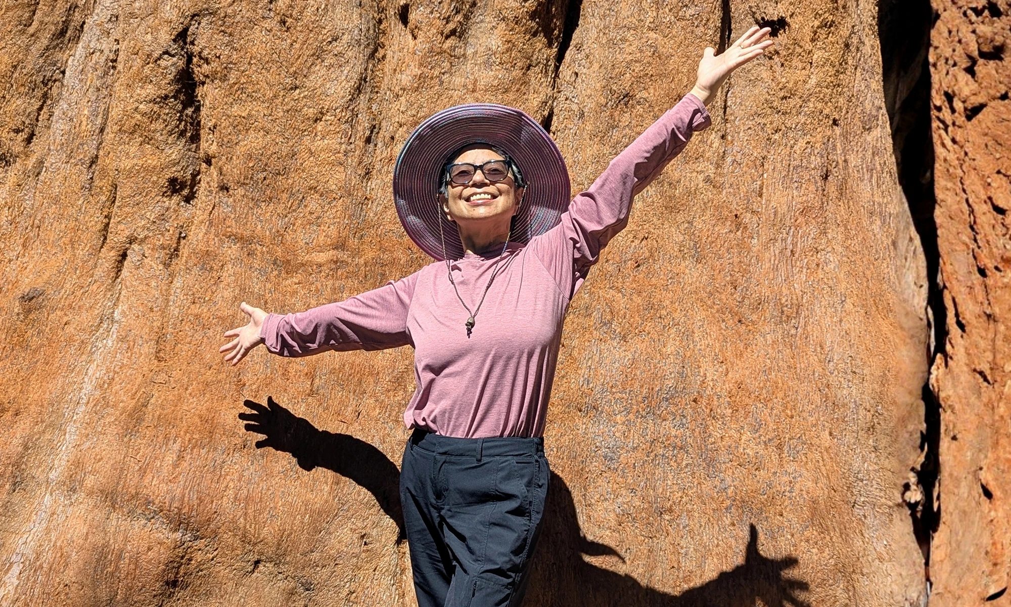 Yin Ling Leung stands at the base of Moro Rock with her arms raised.
