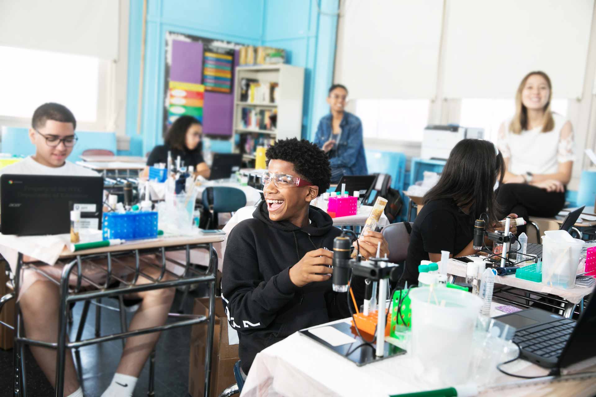 University Heights High School students laugh and talk with each other with a science experiment kit